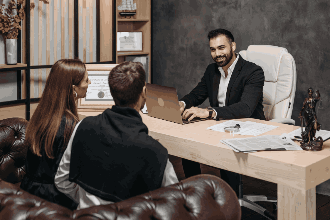 A man and woman collaborate at a desk, focused on a laptop in front of them
