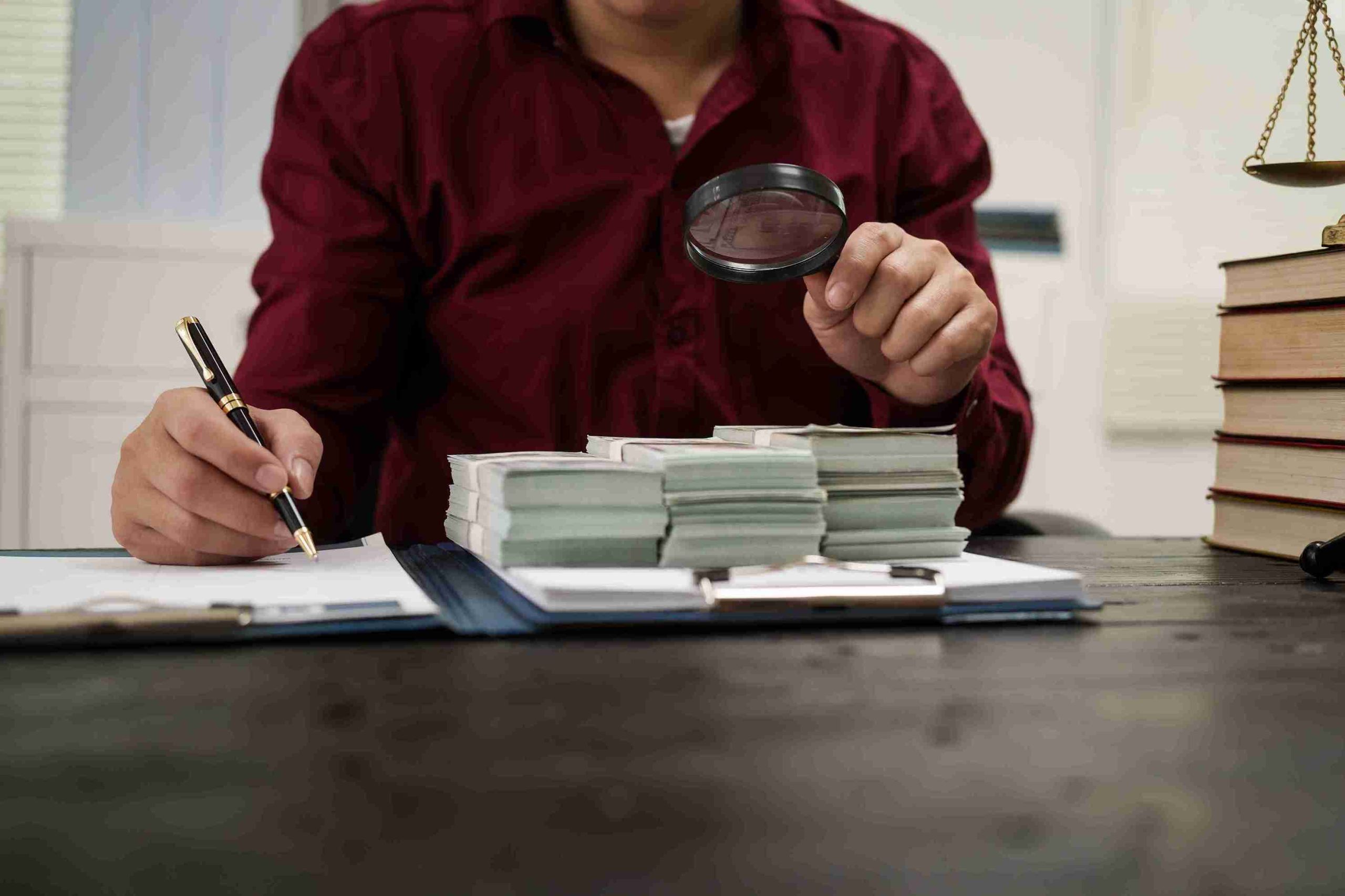 A man uses a magnifying glass to write on a piece of paper, focusing intently on his task.