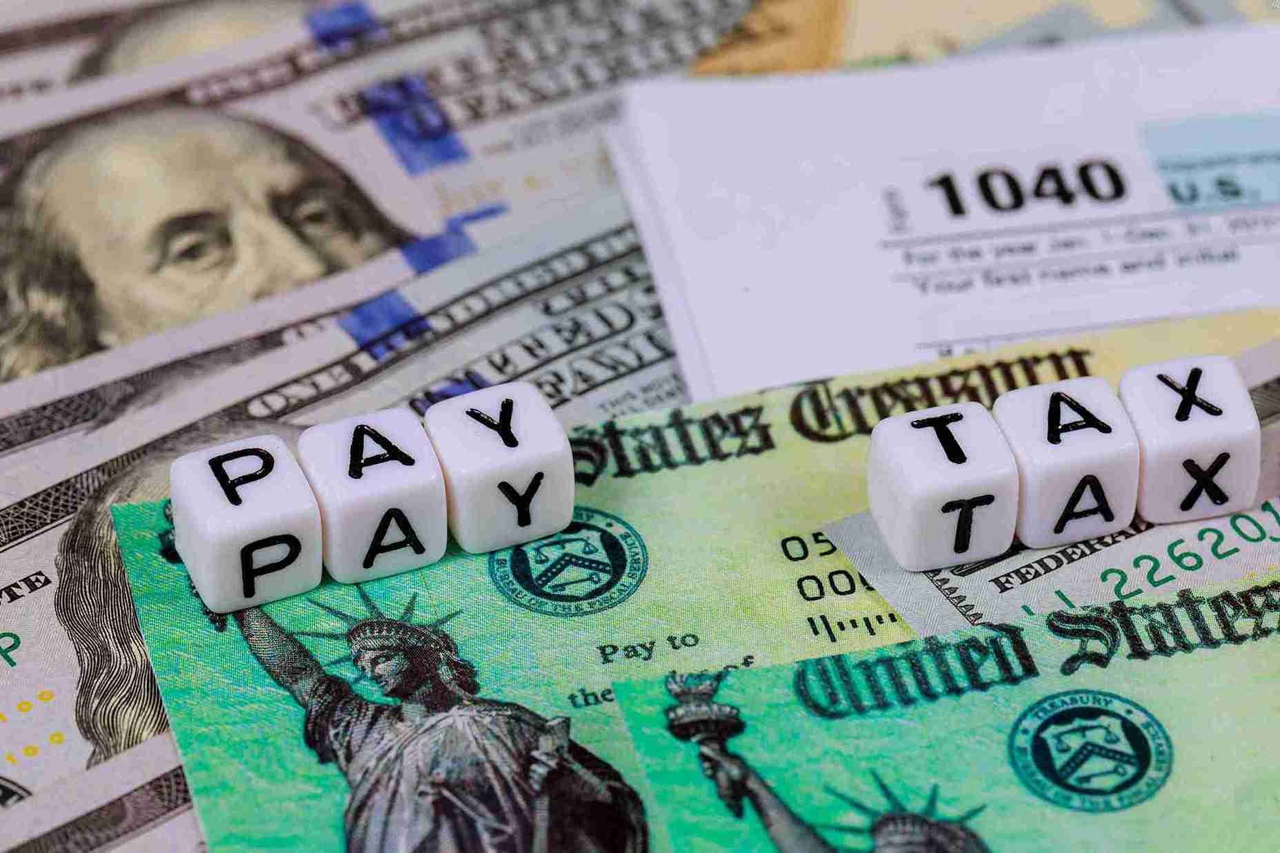 Image of a calculator, tax forms, and stacks of coins representing financial planning and tax preparation.