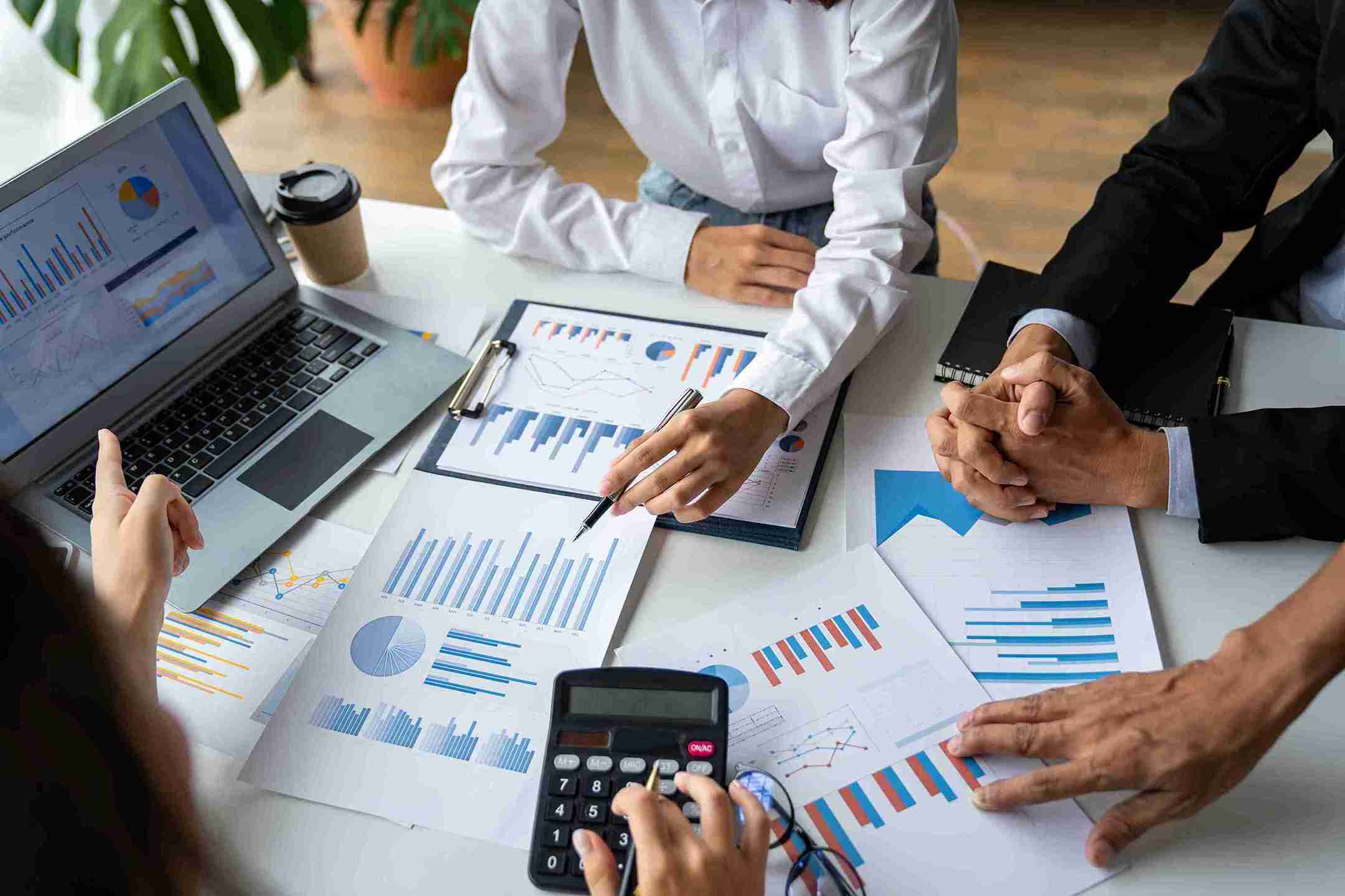 Business professionals collaborating over a laptop and documents, focused on their tasks in a modern office setting.
