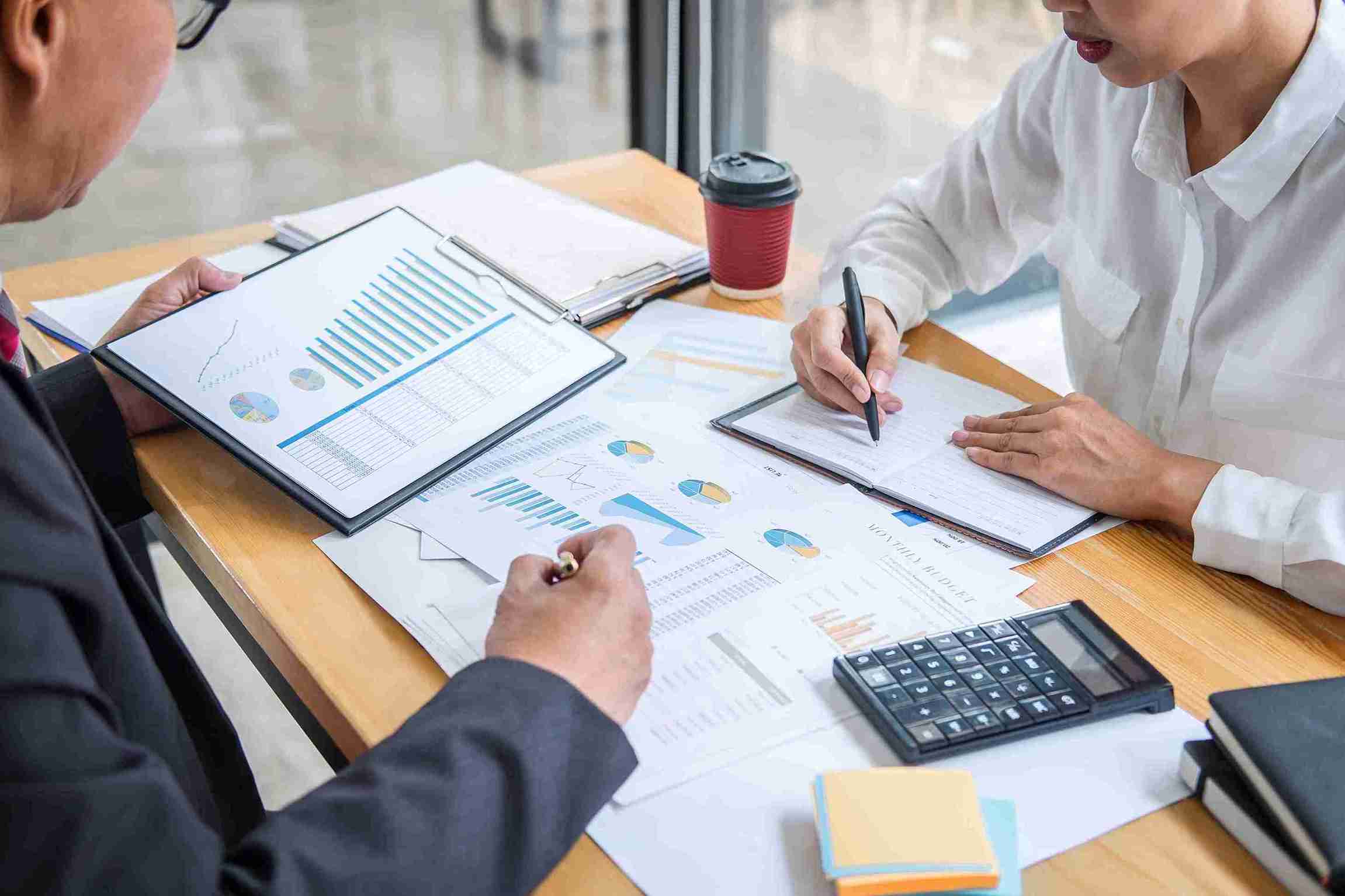Two business professionals collaborate on a document at a desk, focused and engaged in their work.