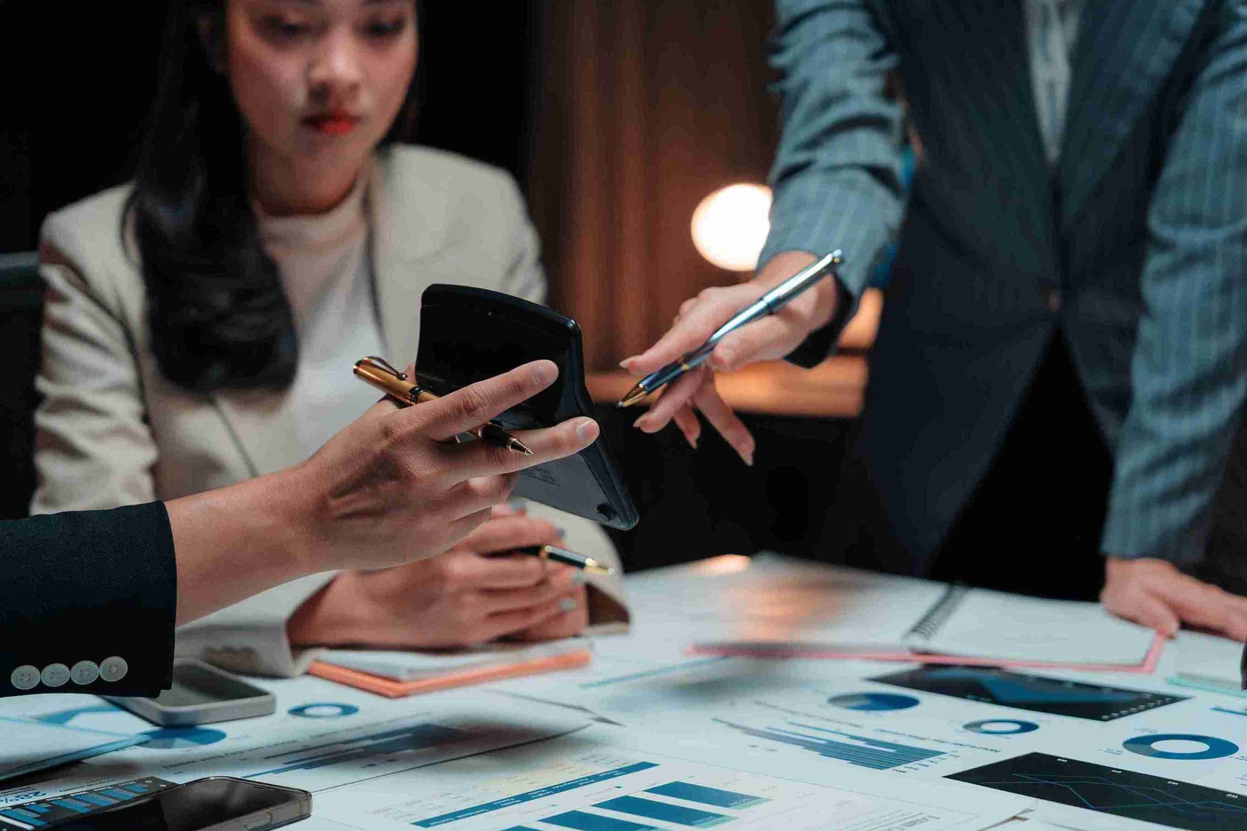 Business professionals collaborating on a laptop and phone, focused on their tasks in a modern office setting.
