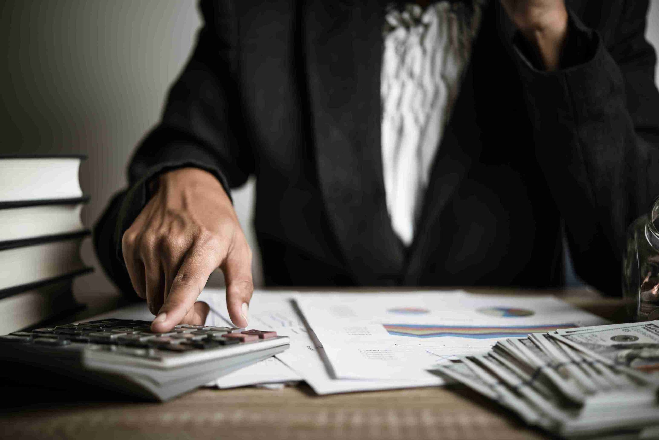 A person in a suit calculates money using a calculator, focused on their task in a professional setting.