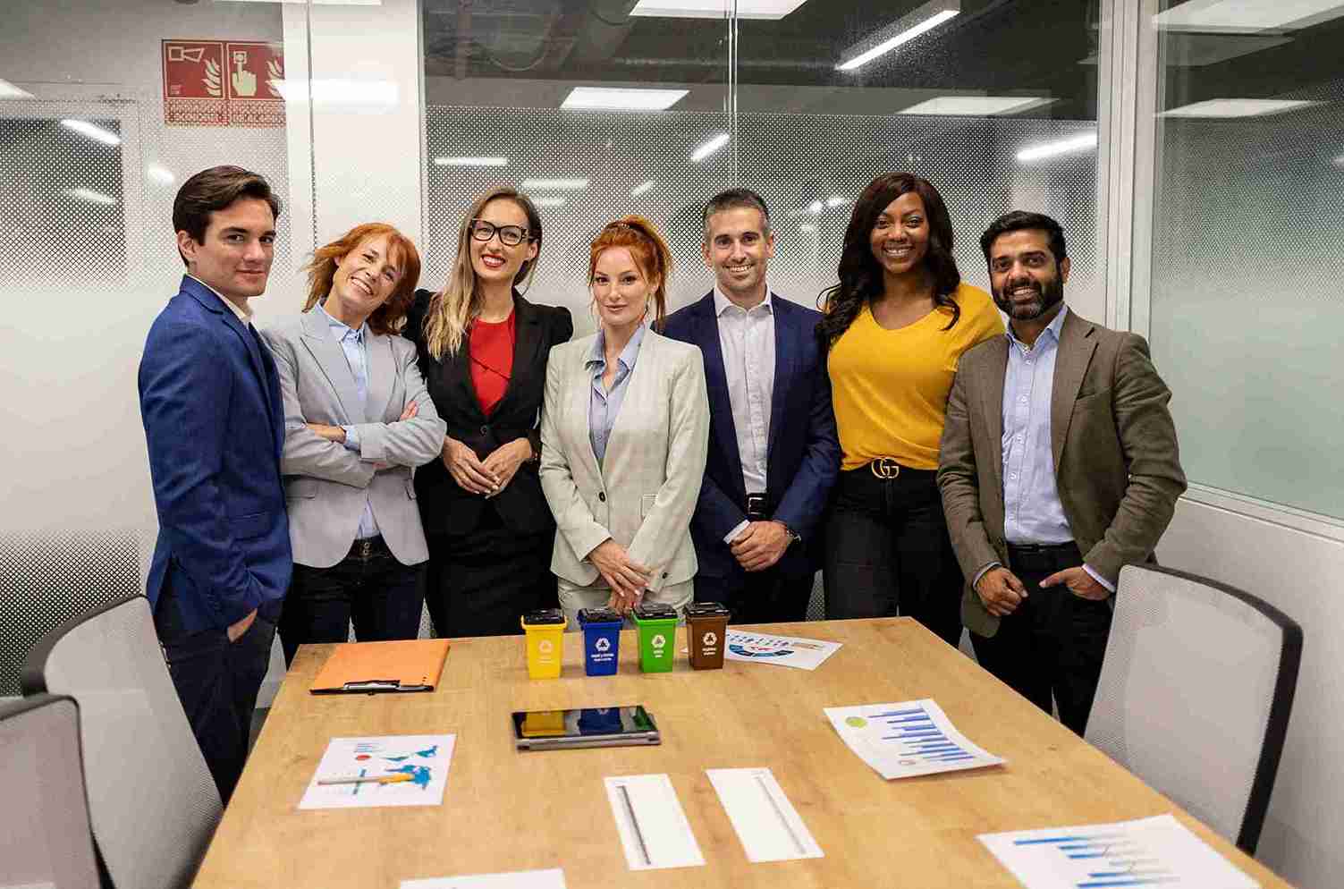A diverse group of business professionals smiling together for a photo in a modern office setting.