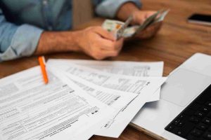 Picture shows a Tax return sheet that need to be filled, while having tax return written on wooden dices as well.
