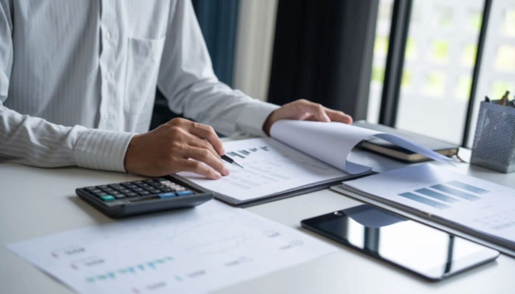 Close-up of a person reviewing financial reports and bar charts next to a calculator, symbolizing the process of calculating double taxation relief and foreign tax credits.