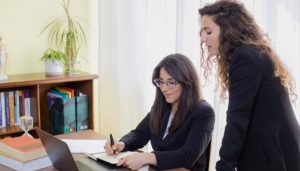 Two female business partners working on property tax and mortgage interest calculations.