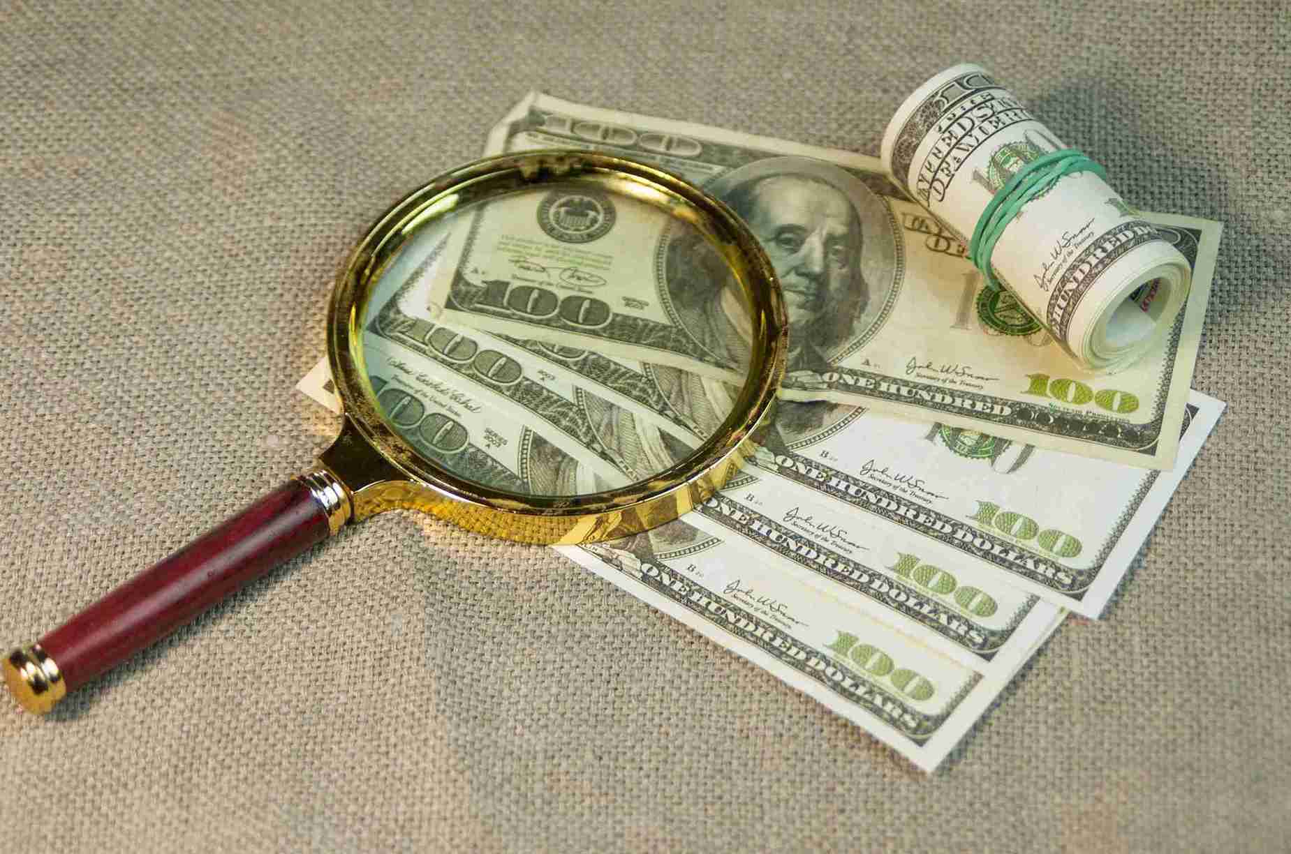 A magnifying glass resting on a stack of coins, symbolizing financial scrutiny and analysis.